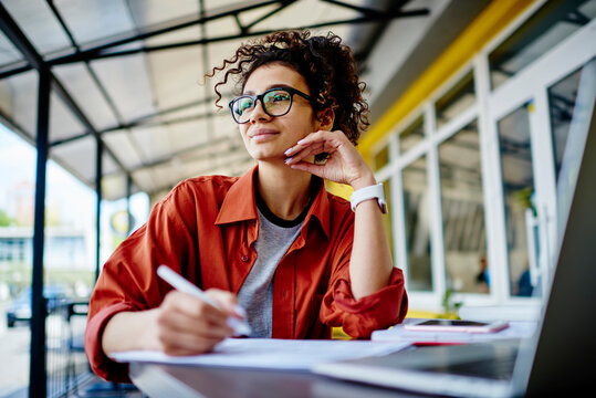 Dreamy woman doing homework in cafe