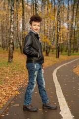 Curly brown-haired boy with a mohawk hairstyle in a leather jacket on an autumn background