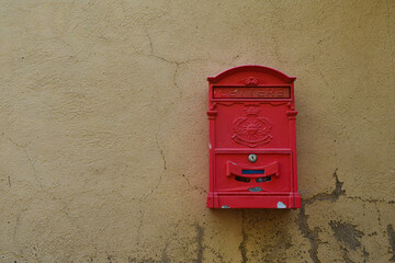 Close-up of an old yellowish wall with a red mailbox, Tuscany, Italy