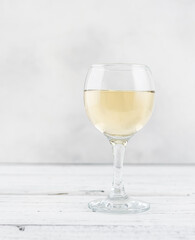 A glass of white grape wine on a light wooden table