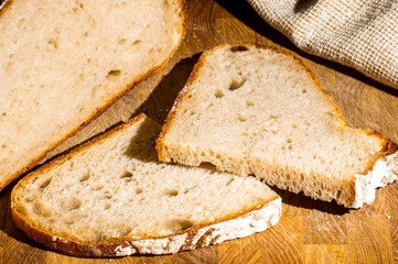 Still life - yeast-free buckwheat bread with sliced pieces, and a linen napkin on a wooden board, a wooden background, hard light, a photo in a low key.