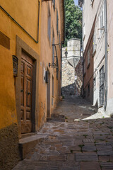 A narrow uphill alley in the historic centre of the medieval village in summer, Castagneto...