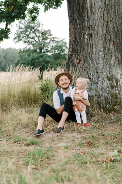 Cheerful father with little kid playing near tree in nature