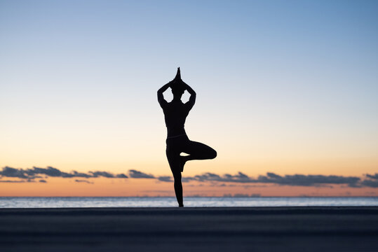 Unrecognizable female meditating in Vriksasana pose at sundown
