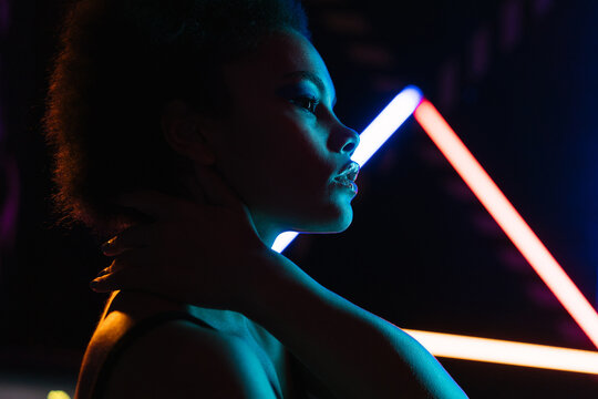 Fashionable black model with makeup against neon projection
