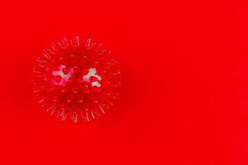 red medical massager in the form of a ball with spikes on a red background with a copy space