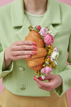 Cropped view of woman holding croissant with flowers