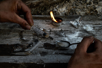 An addict prepares a dose of drugs. A syringe with a dose in your hand prepared on a spoon. The concept of drug addiction, the use of prohibited substances and drugs.