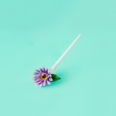 Floral spoon for eating. Minimal concept of spring flowers on mint blue background.