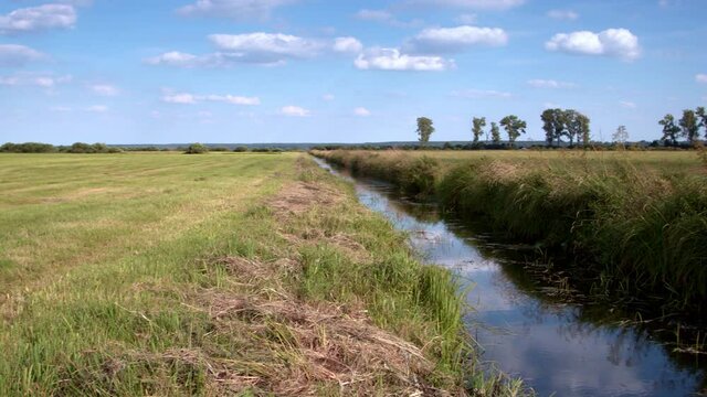 Canal ditch with water landscape view at drained wetland. Camera slide. Natura 2000 Bagno Pulwy protected area in Poland. 