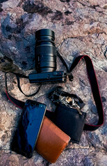Camera, cellphone, wallet and keys on a rock background