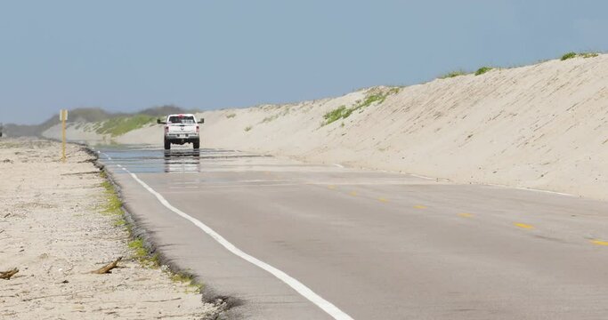 Truck driving on hot road with mirage and sand dunes