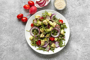 Healthy salad with greens, avocado, tomatoes and res onion, top view