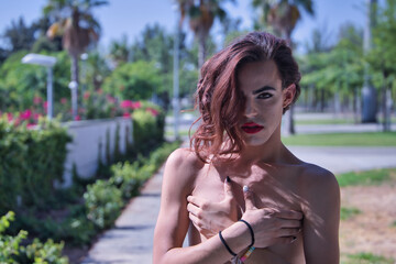 Young adult Hispanic transsexual girl covering her undeveloped breasts with her hands. Concept of...
