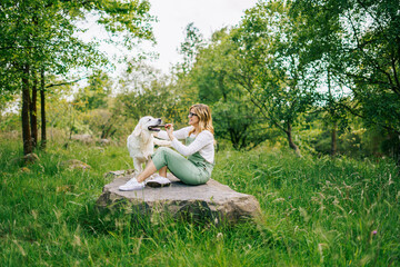 A woman plays with a stick with her dog


