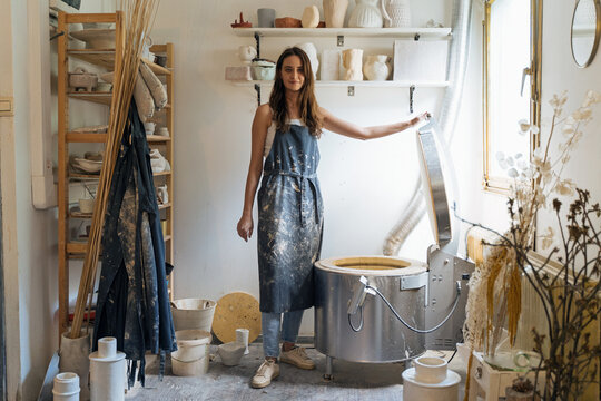 Female potter standing near electric kiln