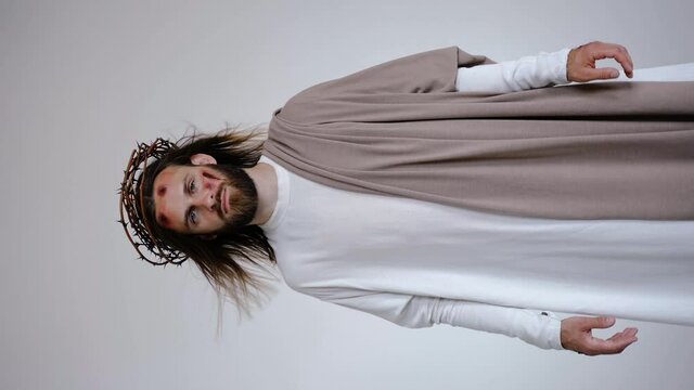 Jesus with wounds on his head and stigmata on his hands looks at the camera on a white background. Studio. High quality 4k footage