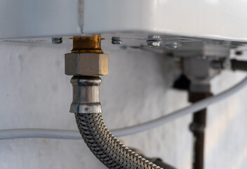 Flexible hose screwed into the base of a gas heater.