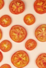 Fresh slices of red tomato are lying on a pink background