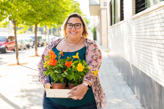 Portrait Of Confident Happy Woman With Plants In Street