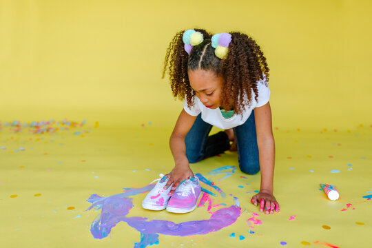 Girl with pigtails fingerpainting shoes