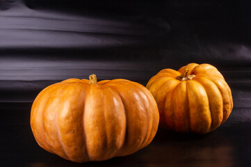 Two whole fresh orange big pumpkin on black background, closeup. Organic agricultural product, ingredients for cooking, healthy food vegan.