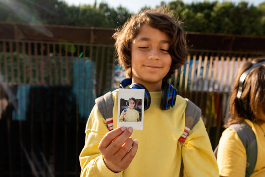 Boy showing at camera his instant photo