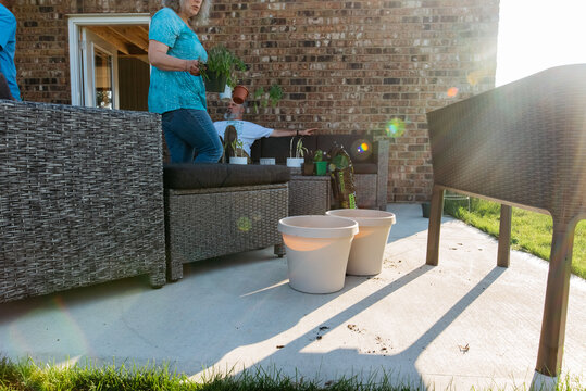 Woman carrying plants out of garage. 