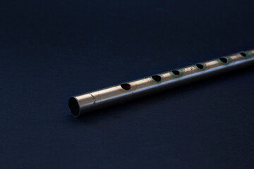 Tin whistle, brass over black background. Close up photography