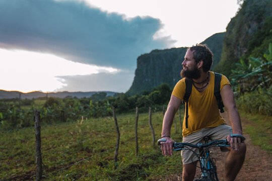 Bearded man riding bicycle in countryside