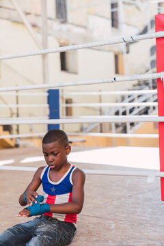 Concentrated Teen In Boxing Gloves Sitting Near Ring