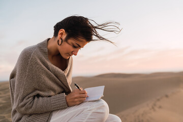 Woman with notebook sitting on sand