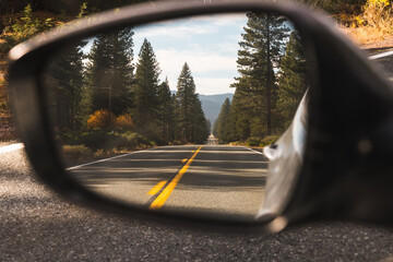 Side view mirror of car with reflection of road
