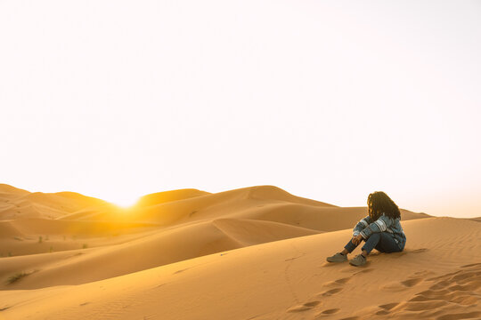 woman sitting in sandy dunes in desert