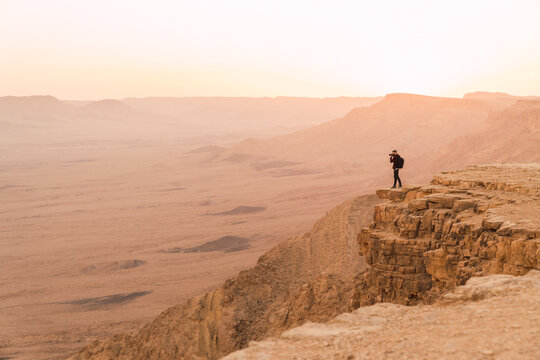 Man standing on a cliff during susnet.