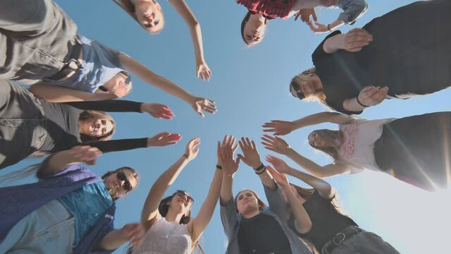Eleven cheerful girlfriends make their hands together on a sunny day.