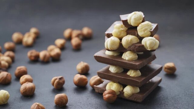 Chocolate tower with hazelnuts. Pieces of chocolate with hazelnuts on a black background. nuts roll on the black table, recipe for making chocolate with nuts