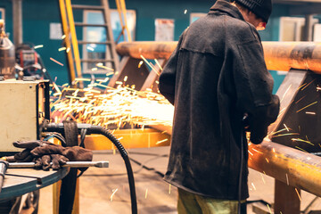 an employee in a metalworking shop cuts a metal product