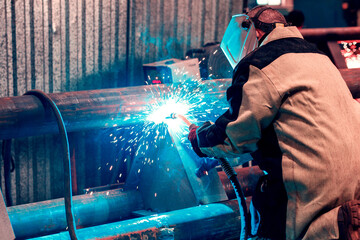 a man in overalls welds metal joints