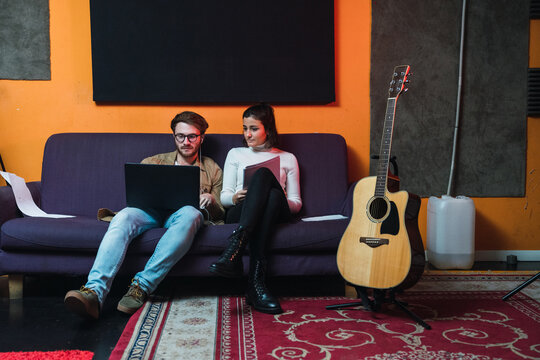 Couple sitting on a sofa in music studio.