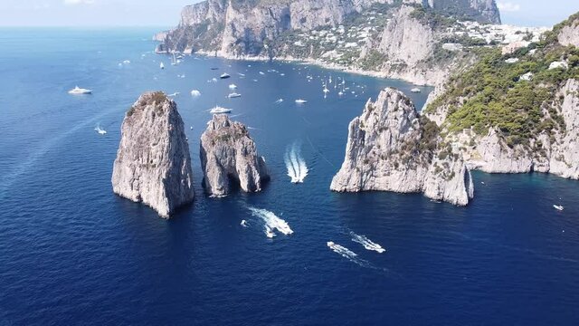 Aerial drone view of boats crossing sea stacks in the Island Of Capri, Italy