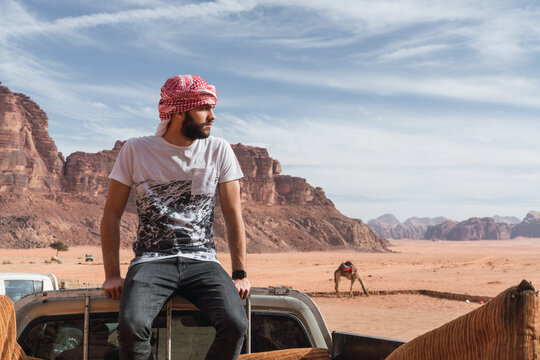 Arabic man on car between sand lands in desert