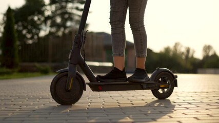 Girl rides an electric scooter. Child travel cheerfully. Empty city street. Legs on an electric scooter. Girl travel on scooter. Child on deserted street. Electric scooter close up. City travel girl