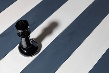 black chess piece queen stands on the white line and casts a shadow. shadows from the queen
