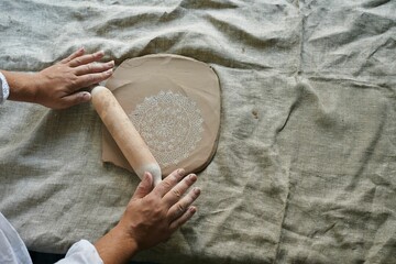 master craftsman rolls the clay on the table, transfers the napkin pattern to the clay mass