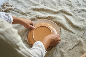 master craftsman rolls the clay on the table, transfers the napkin pattern to the clay mass