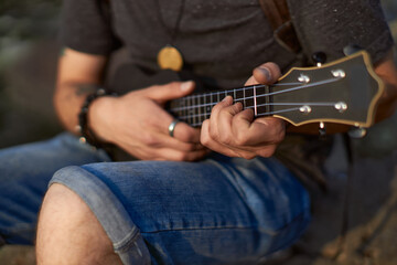 men's hands play the black ukulel, clutching the strings with their hands. High quality photo