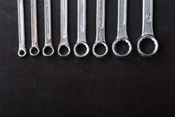 A set of wrenches in a row on a black background in a row.