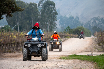 Women and men on ATVs are enjoying a ride in a field