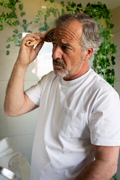 Senior Man Combing His Hair With A Brush